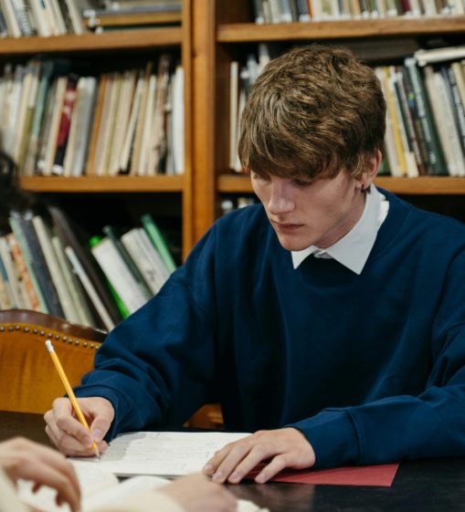 Two students studying intensely in a library environment, surrounded by books.